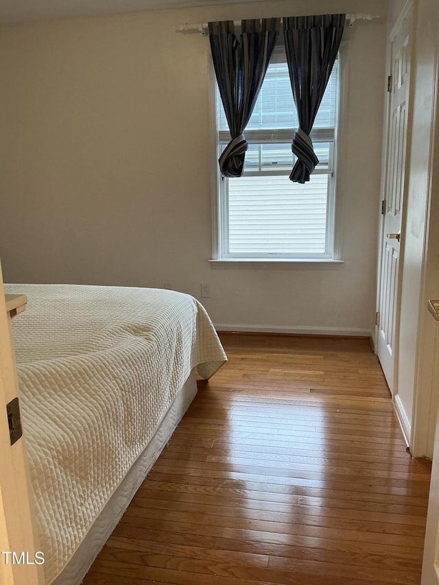 bedroom featuring baseboards, multiple windows, and hardwood / wood-style floors
