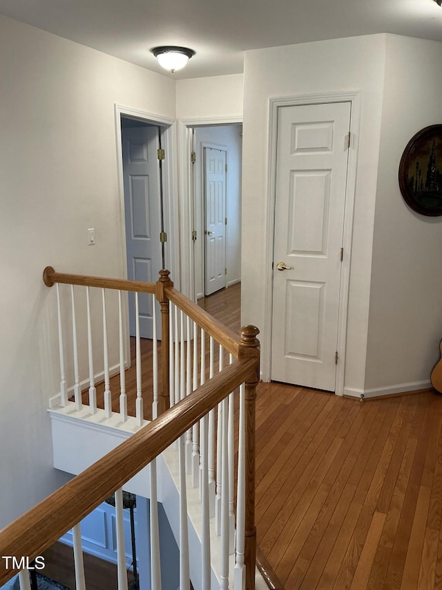hall featuring baseboards, an upstairs landing, and hardwood / wood-style flooring