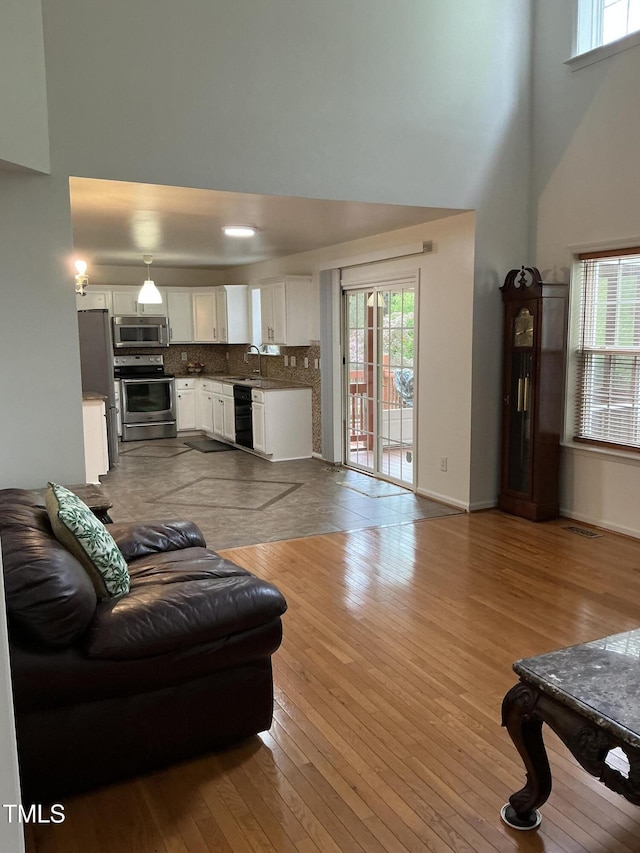 living room with hardwood / wood-style flooring, a high ceiling, visible vents, and a healthy amount of sunlight