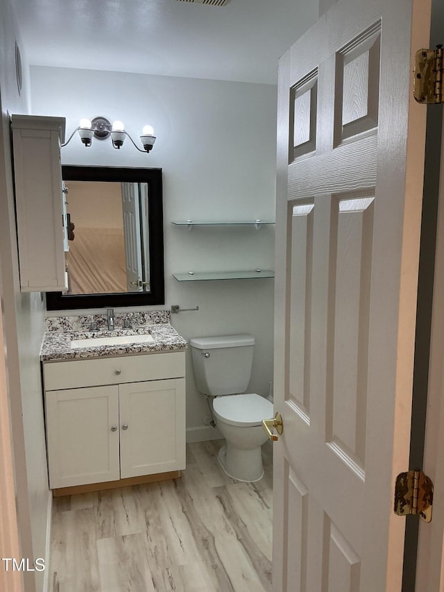 bathroom with toilet, wood finished floors, and vanity