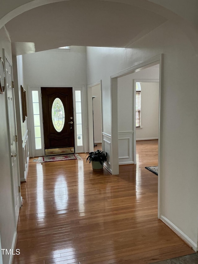 foyer entrance featuring arched walkways, plenty of natural light, and wood-type flooring