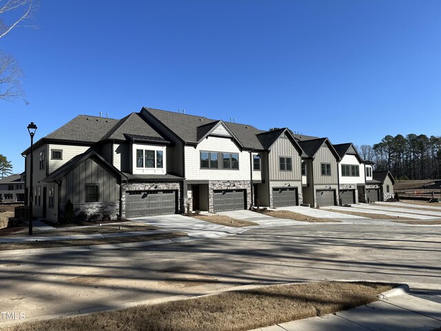 view of front of house with stone siding, a garage, board and batten siding, a residential view, and driveway