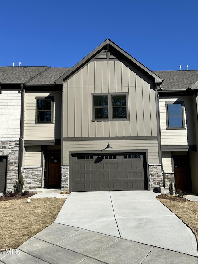 view of front facade featuring a garage, stone siding, concrete driveway, and board and batten siding