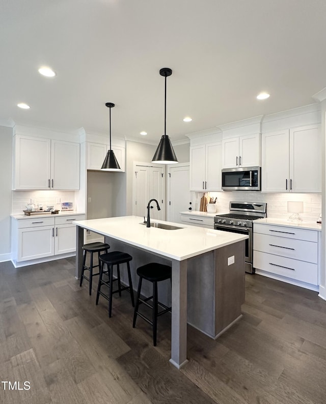 kitchen featuring a sink, backsplash, appliances with stainless steel finishes, and dark wood-style floors