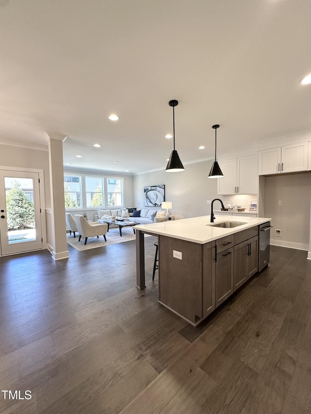 kitchen featuring crown molding, stainless steel dishwasher, a sink, open floor plan, and dark wood-style floors