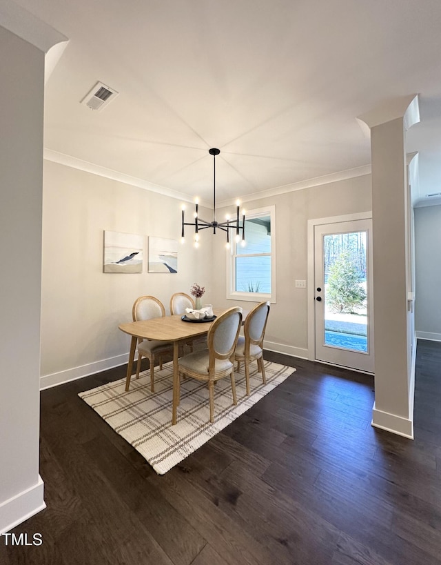dining room with a notable chandelier, dark wood-type flooring, visible vents, and crown molding