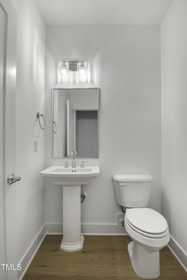bathroom with baseboards, toilet, and wood finished floors