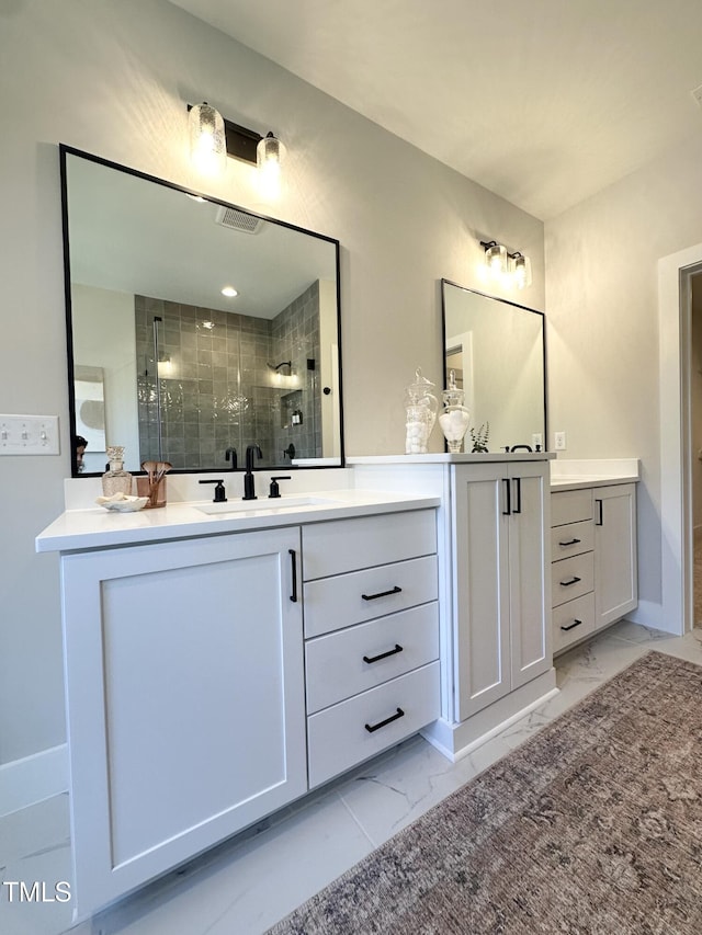 bathroom featuring a shower stall, two vanities, marble finish floor, and a sink