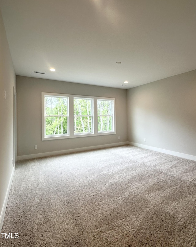 empty room with a healthy amount of sunlight, visible vents, and carpet floors