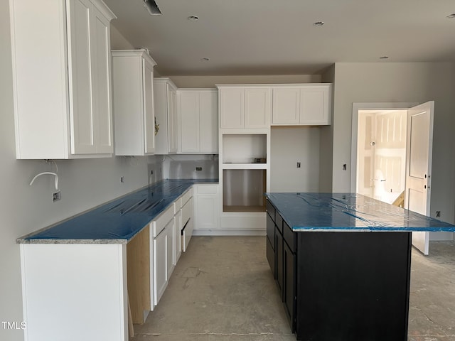 3020 White Rail Dr, Fuquay Varina, NC 27526 - kitchen with unfinished concrete floors, a kitchen island, white cabinets, and dark stone counters