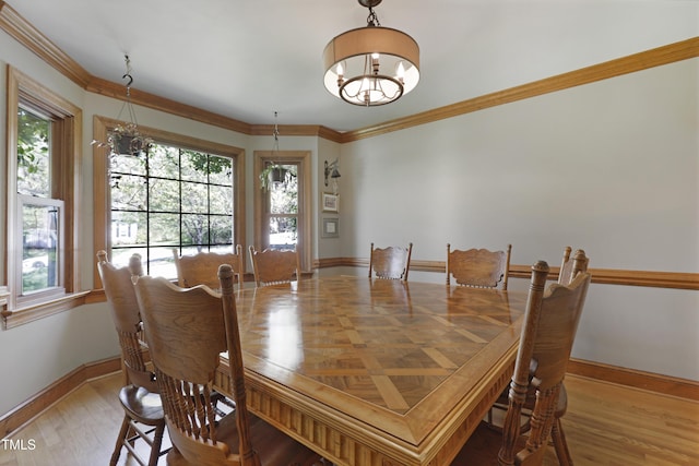 dining area with a chandelier, baseboards, ornamental molding, and wood finished floors