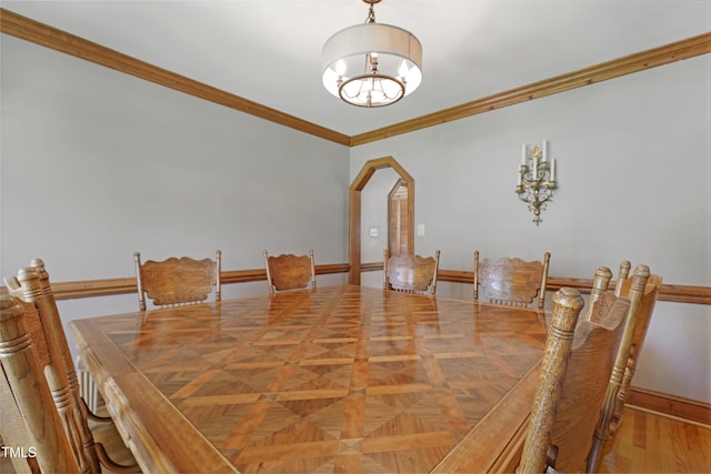dining space with a chandelier, ornamental molding, arched walkways, and baseboards