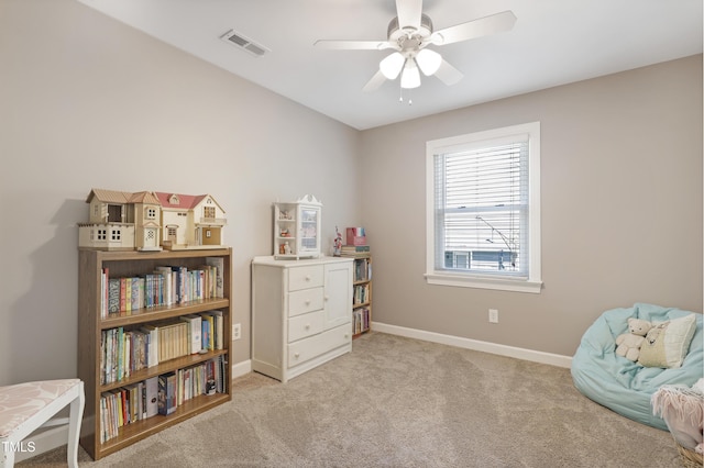 living area featuring light colored carpet, a ceiling fan, and baseboards
