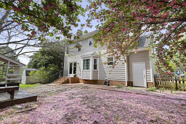 rear view of property with fence, a deck, a shed, an outbuilding, and entry steps