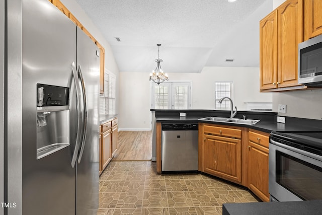 kitchen with a notable chandelier, a sink, dark countertops, a peninsula, and stainless steel appliances