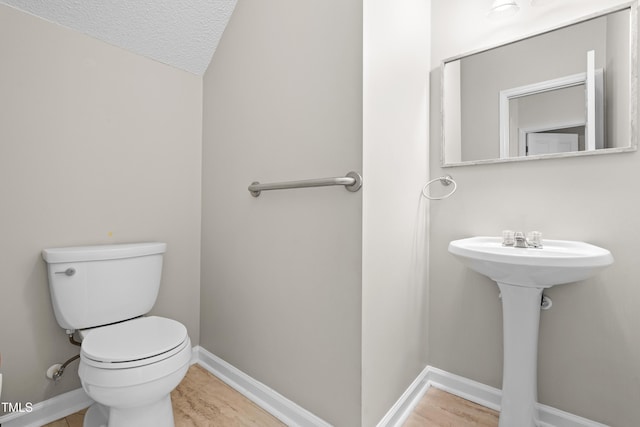 bathroom featuring toilet, a textured ceiling, baseboards, and vaulted ceiling