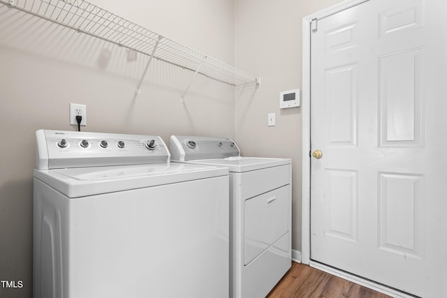 washroom with washer and dryer, laundry area, wood finished floors, and baseboards