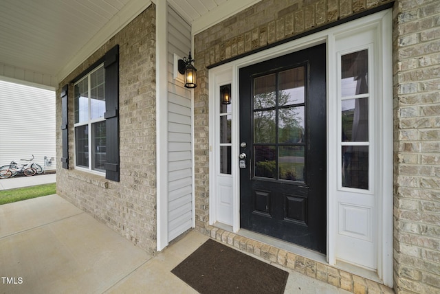 property entrance featuring covered porch and brick siding
