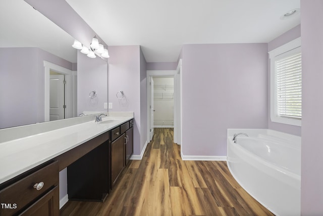 full bath featuring a bath, baseboards, a spacious closet, vanity, and wood finished floors