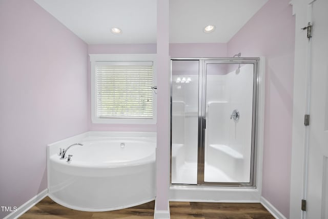 full bathroom with a shower stall, a bath, and wood finished floors