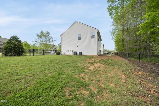 rear view of house with central air condition unit, a fenced backyard, and a lawn