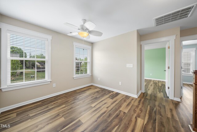 spare room featuring wood finished floors, ceiling fan, baseboards, and visible vents
