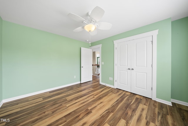 unfurnished bedroom with a closet, ceiling fan, baseboards, and wood finished floors