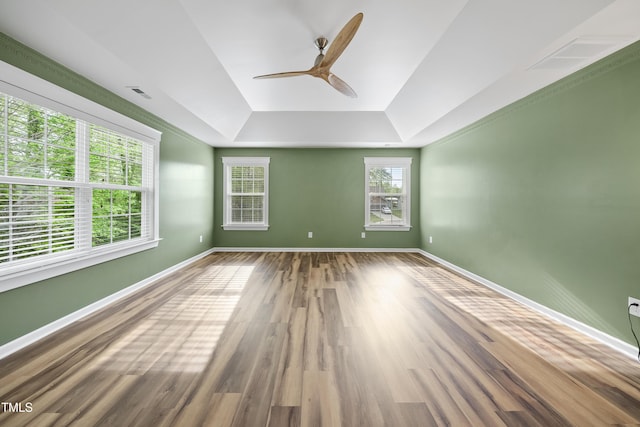 unfurnished room featuring a tray ceiling, baseboards, a ceiling fan, and visible vents