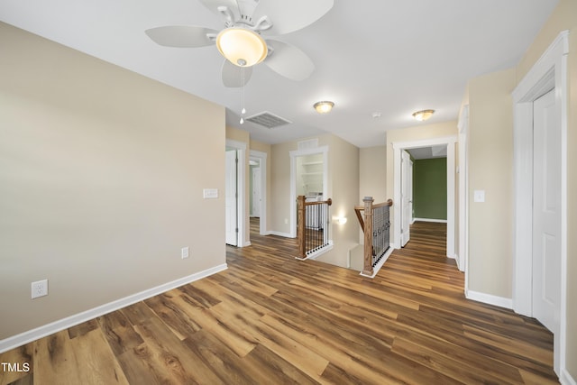unfurnished room featuring ceiling fan, visible vents, baseboards, and wood finished floors
