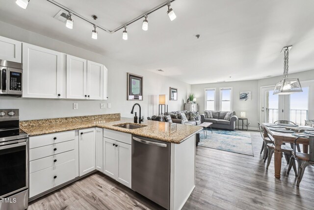 790 New River Inlet Rd Unit 113B, North Topsail Beach, NC 28460 - kitchen featuring stainless steel appliances, a sink, a peninsula, light wood-style flooring, and white cabinetry