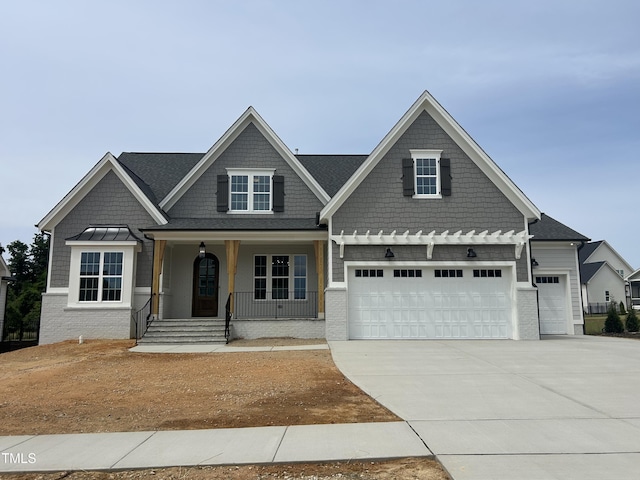 craftsman inspired home featuring concrete driveway, a porch, and an attached garage