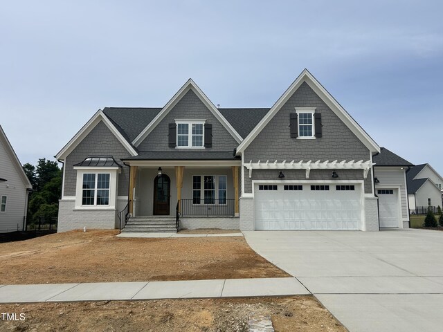 craftsman-style house featuring a porch, driveway, and an attached garage