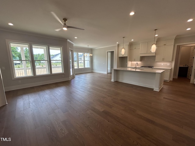 kitchen featuring ornamental molding, a sink, baseboards, ceiling fan, and white cabinets