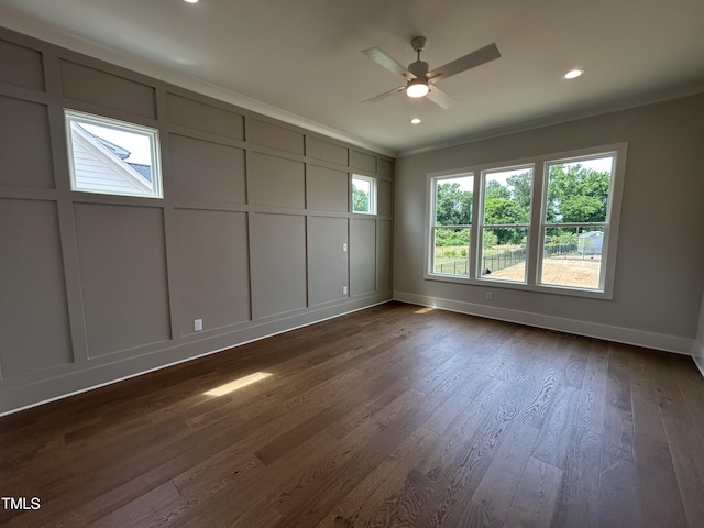 unfurnished room with ceiling fan, a decorative wall, ornamental molding, baseboards, and dark wood-type flooring