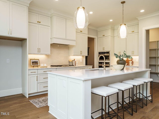 921 Lily Claire Ln, Fuquay Varina, NC 27526 - kitchen with dark wood-style floors, backsplash, an island with sink, crown molding, and recessed lighting