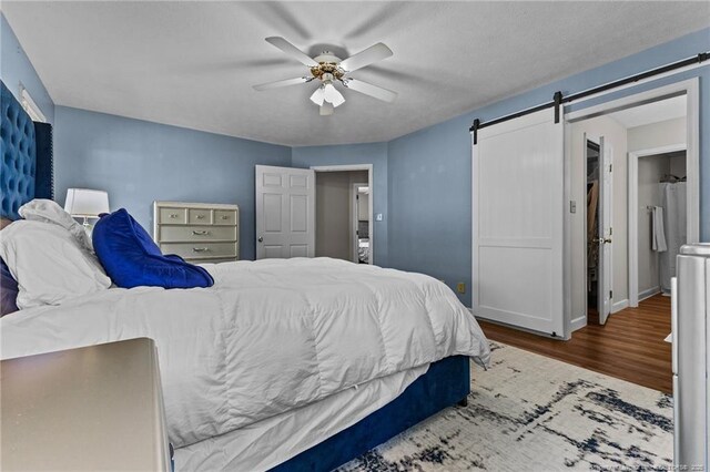 7783 Trappers Rd, Fayetteville, NC 28311 - bedroom with a barn door, baseboards, a ceiling fan, and wood finished floors