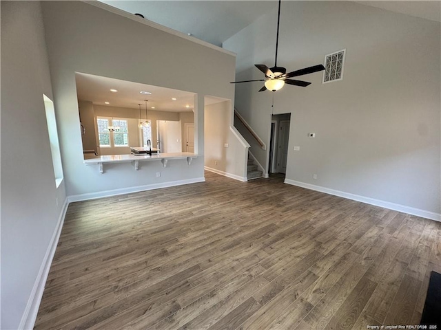unfurnished living room featuring visible vents, baseboards, a ceiling fan, stairs, and dark wood-type flooring