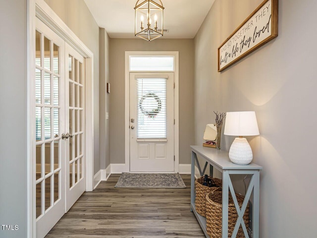 entryway with a chandelier, wood finished floors, plenty of natural light, and baseboards