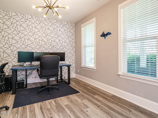 home office with an accent wall, baseboards, a chandelier, and wood finished floors