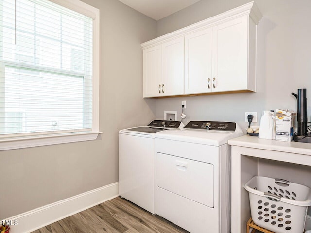 laundry room featuring washing machine and clothes dryer, cabinet space, light wood finished floors, and baseboards