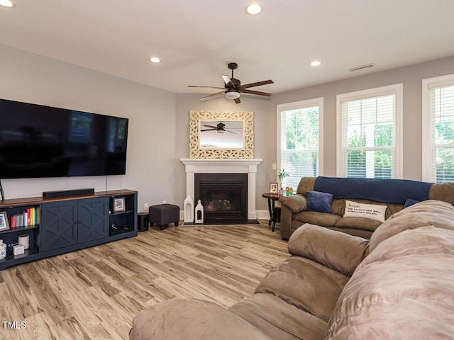 living area with ceiling fan, recessed lighting, light wood-type flooring, plenty of natural light, and a fireplace with flush hearth