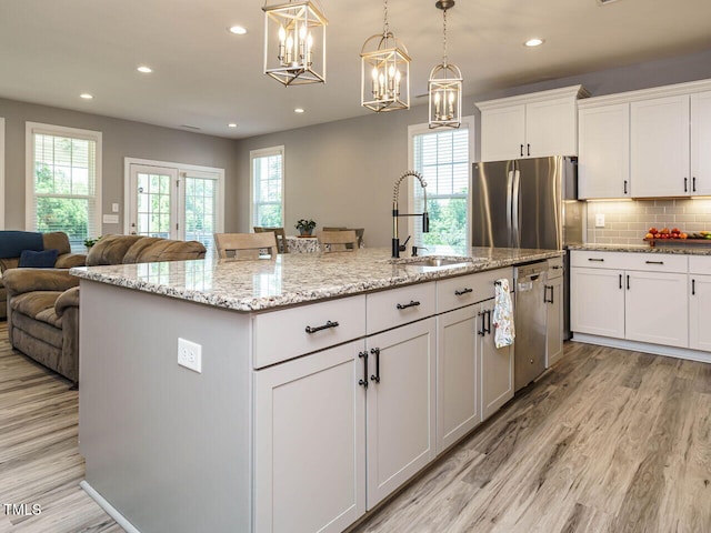 kitchen with a sink, stainless steel appliances, light wood-style floors, open floor plan, and recessed lighting