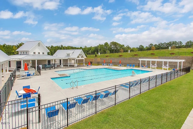 community pool with a water slide, a patio, and view of scattered trees