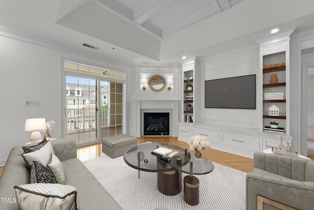 living room featuring ornamental molding, light wood finished floors, a glass covered fireplace, and visible vents