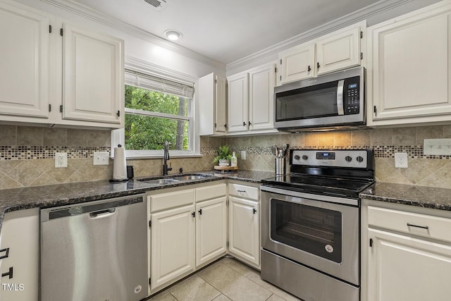 105 Cavendish Dr, Cary, NC 27513 - kitchen featuring appliances with stainless steel finishes, a sink, crown molding, light tile patterned flooring, and dark stone countertops