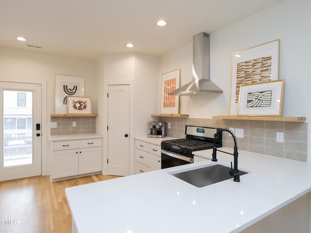 612 E Ellerbee St, Durham, NC 27704 - kitchen with wall chimney exhaust hood, stainless steel range with gas stovetop, a sink, light countertops, and light wood-style floors