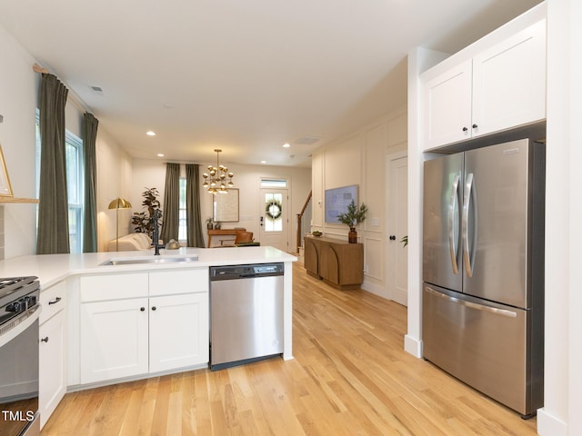 612 E Ellerbee St, Durham, NC 27704 - kitchen with stainless steel appliances, a peninsula, a chandelier, light wood-type flooring, and recessed lighting