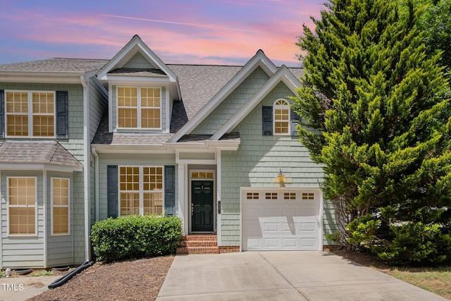 view of front facade featuring driveway, a shingled roof, and an attached garage