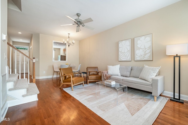 living room with a chandelier, wood finished floors, stairs, a ceiling fan, and baseboards
