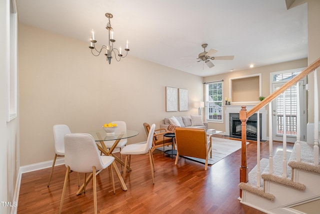 dining space featuring wood finished floors, a premium fireplace, a ceiling fan, and baseboards